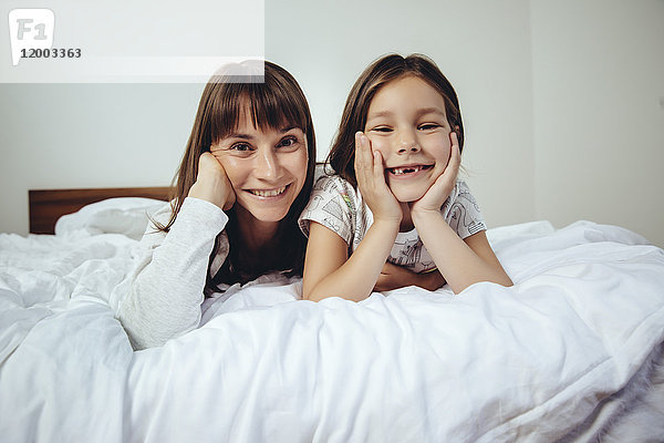 Porträt der glücklichen Mutter und Tochter im Bett