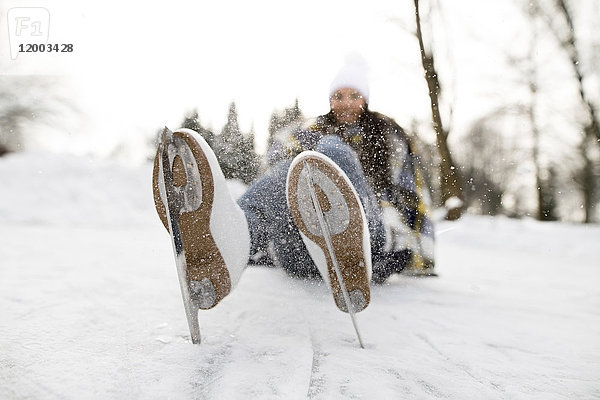 Frau mit Schlittschuhen auf Schnee liegend