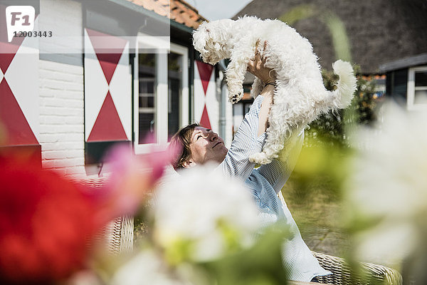 Frau hält Hund auf der Terrasse