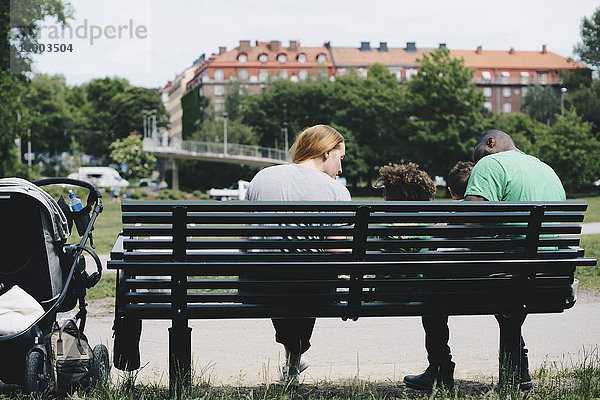 Rückansicht der Familie auf der Bank im Park in der Stadt