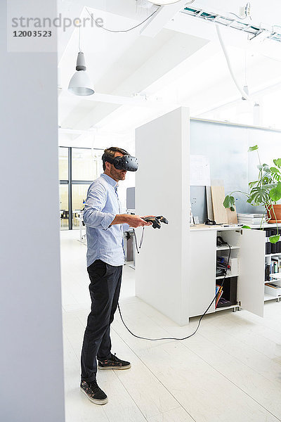 Geschäftsmann mit Virtual-Reality-Stimulator im Kreativbüro