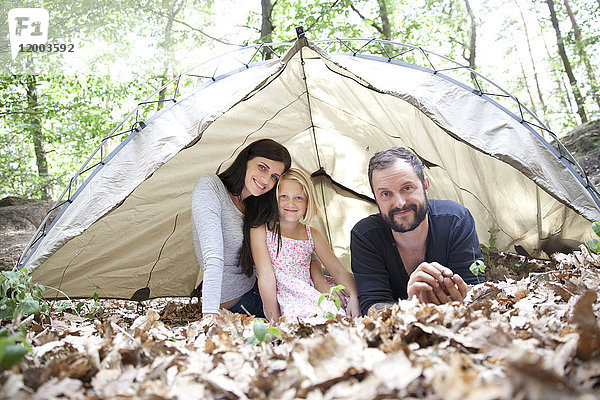 Porträt einer glücklichen Familie mit Tochter im Zelt im Wald