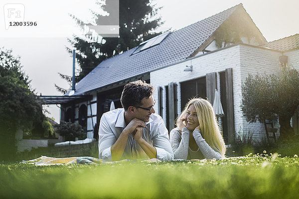 Glückliches reifes Paar auf der Wiese vor dem Haus liegend