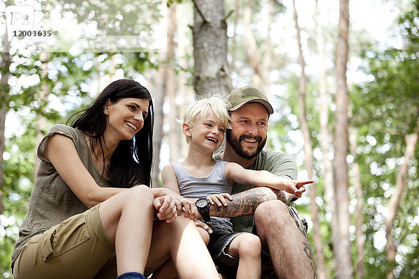 Glückliche Familie mit Sohn im Wald sitzend