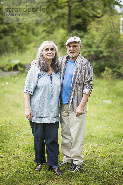 Porträt eines älteren Ehepaares auf Rasen im Hinterhof