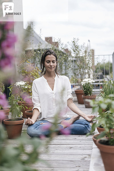 Frau sitzt auf dem Balkon und praktiziert Yoga