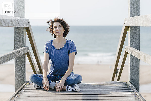 Porträt einer Frau  die auf einer Strandpromenade sitzt.
