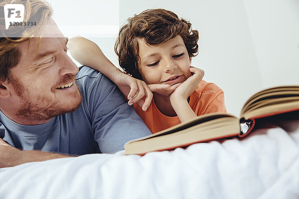 Vater und Sohn lesen Buch im Bett