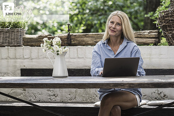 Reife Frau auf der Terrasse sitzend  mit Laptop