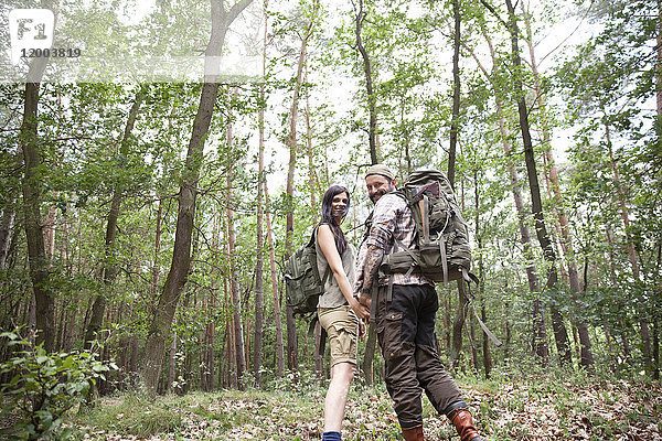 Glückliches Paar mit Rucksäcken auf einer Wanderung im Wald