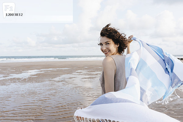 Glückliche Frau mit Tuch am Strand