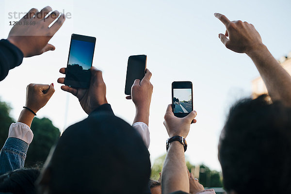 Low-Winkel-Ansicht von Freunden  die von Smartphones aus gegen den Himmel fotografieren.