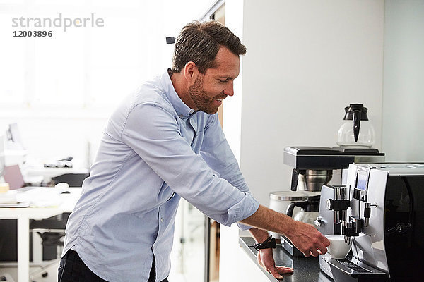 Geschäftsmann mit Kaffeemaschine an der Küchentheke im Kreativbüro
