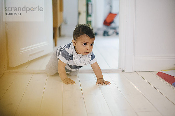 Kleinkind schaut weg  während es zu Hause auf dem Boden krabbelt.
