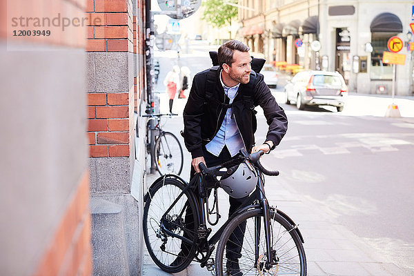Geschäftsmann mit Fahrrad auf der Straße in der Stadt bei Sonnenschein
