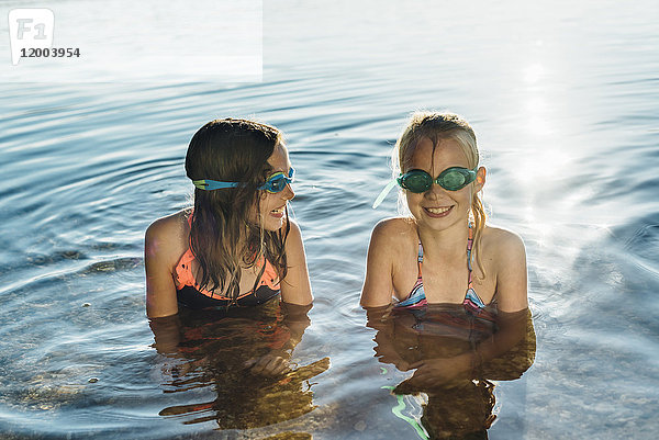 Zwei lächelnde Freunde mit Schwimmbrille am Seeufer