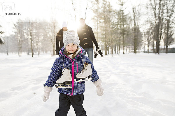 Kleines Mädchen beim Schlittschuhlaufen mit ihren Eltern