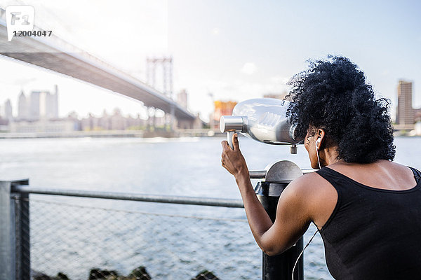 USA  New York City  Brooklyn  Frau blickt durch Münzferngläser an der Manhattan Bridge