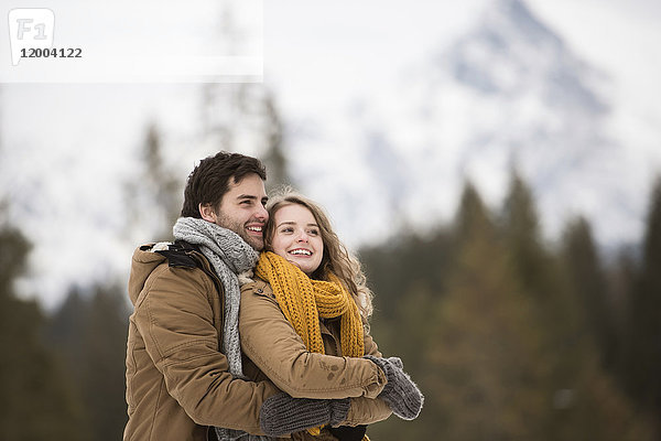 Porträt eines glücklichen jungen Paares in Winterlandschaft