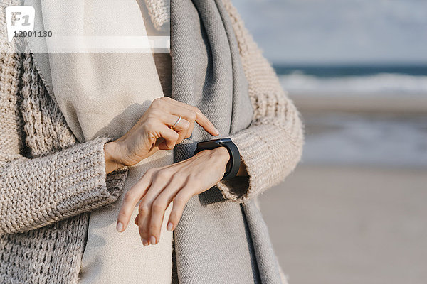 Frau am Strand überprüft ihre Smartwatch