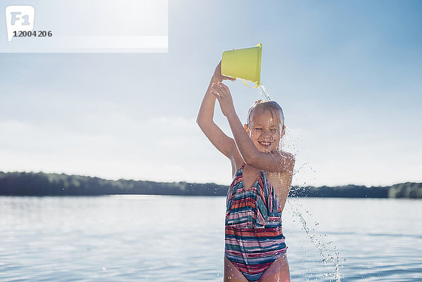Porträt eines lächelnden Mädchens  das Wasser über den Kopf gießt.
