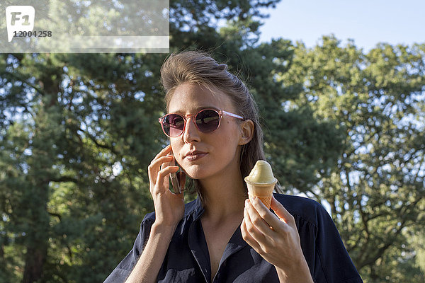 Junge Frau mit Eiszapfen mit Smartphone