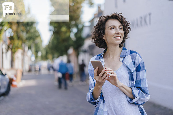 Lächelnde Frau mit Handy in der Stadt
