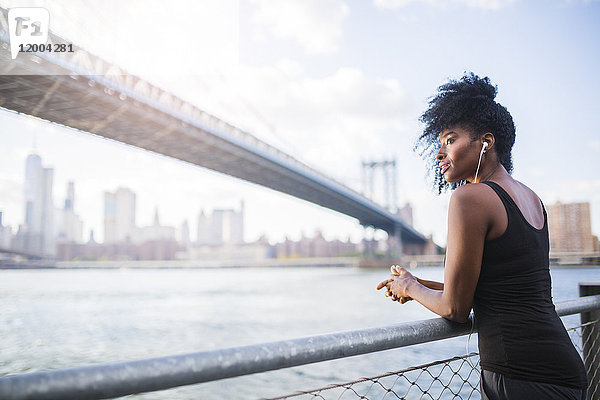 USA  New York City  Brooklyn  Frau hört Musik in der Nähe von Manhattan Bridge