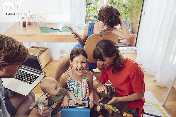Glückliche spielerische Familie mit digitalen Geräten im Kinderzimmer