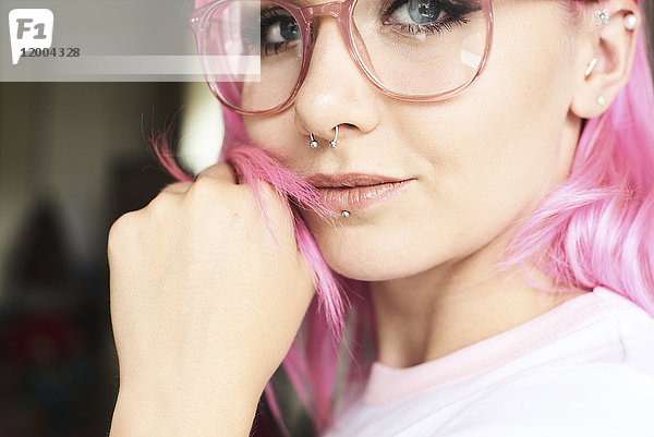 Portrait einer jungen Frau mit rosa Haaren  Brille und Piercings
