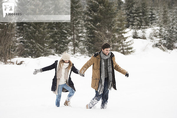 Glückliches junges Paar beim Wandern in verschneiter Winterlandschaft