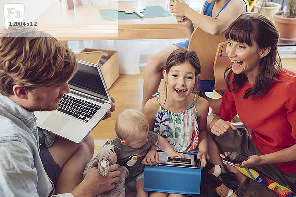 Glückliche spielerische Familie mit digitalen Geräten im Kinderzimmer