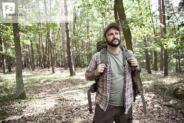 Ernsthafter Mann mit Rucksack auf einer Wanderung im Wald