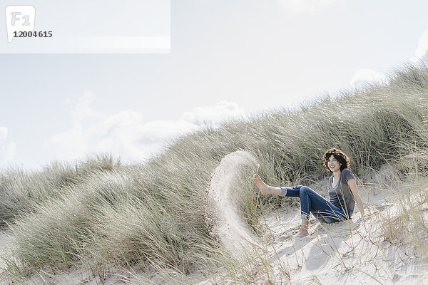 Verspielte Frau sitzt in der Stranddüne