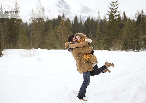 Glückliches junges Paar in verschneiter Winterlandschaft