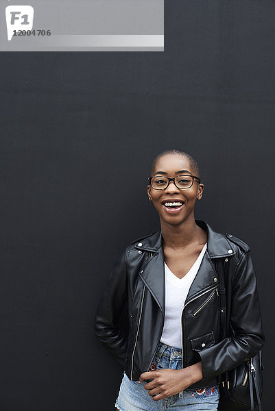 Porträt einer lachenden jungen Frau in schwarzer Lederjacke