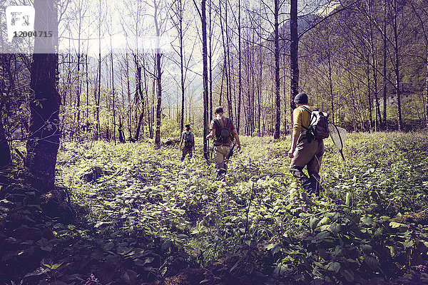 Slowenien  Bovec  drei Angler  die im Wald Richtung Soca-Fluss wandern