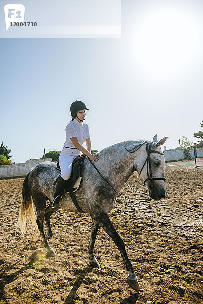 Junge Frau reitet auf einem Pferd