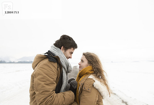 Verliebtes junges Paar auf der Landstraße in schneebedeckter Landschaft