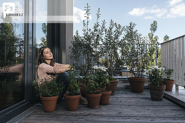 Frau entspannt sich auf dem von Pflanzen umgebenen Balkon