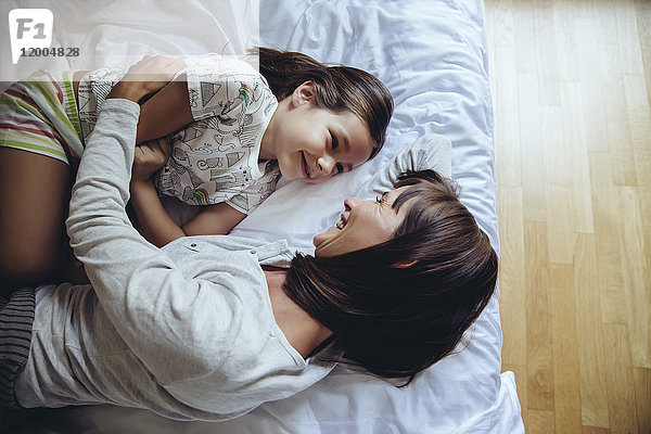 Mutter und Tochter kuscheln auf dem Bett