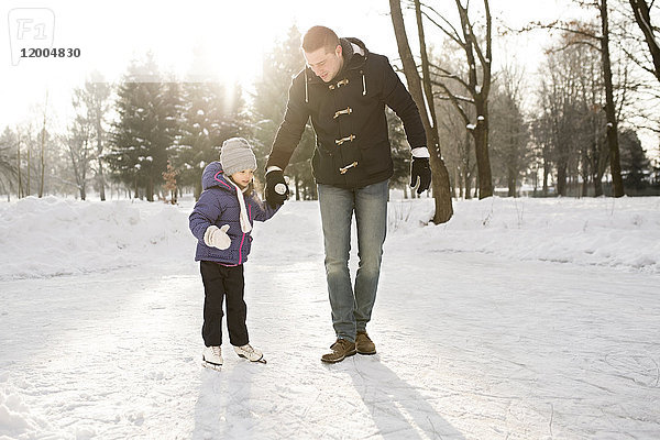 Vater und Tochter Schlittschuhlaufen auf dem zugefrorenen See