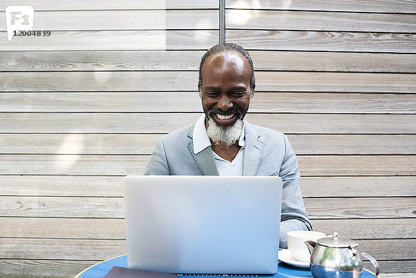 Portrait eines lachenden bärtigen Mannes mit Laptop