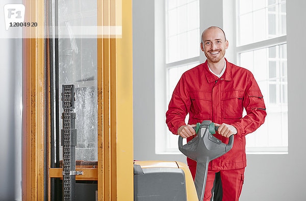Porträt des lächelnden Mannes in der Fabrik mit Gabelstapler