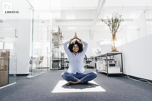 Glückliche junge Frau beim Yoga im Büro