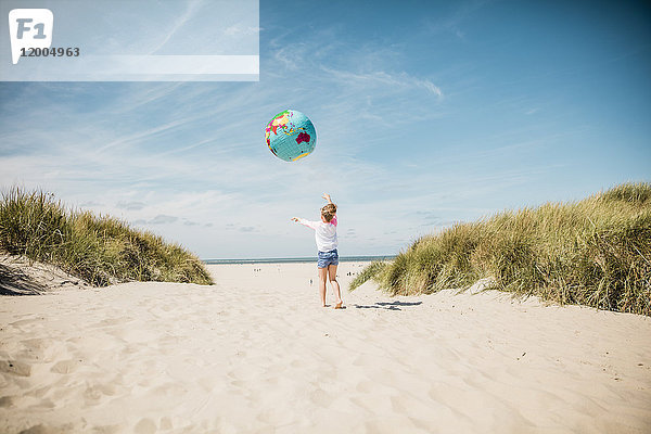 Mädchen spielt mit Globus am Strand
