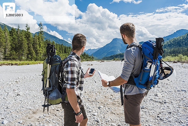 Deutschland  Bayern  zwei Wanderer stehen im trockenen Bachbett und orientieren sich mit Handy und Karte.