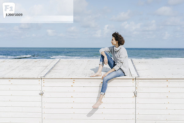 Frau auf Holzkiste am Strand sitzend