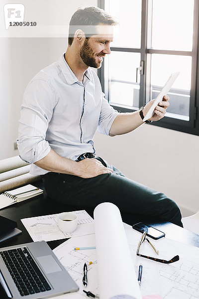Architekt sitzend auf dem Schreibtisch in seinem Büro mit Tablette