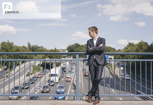 Geschäftsmann steht auf einer Brücke über eine Autobahn